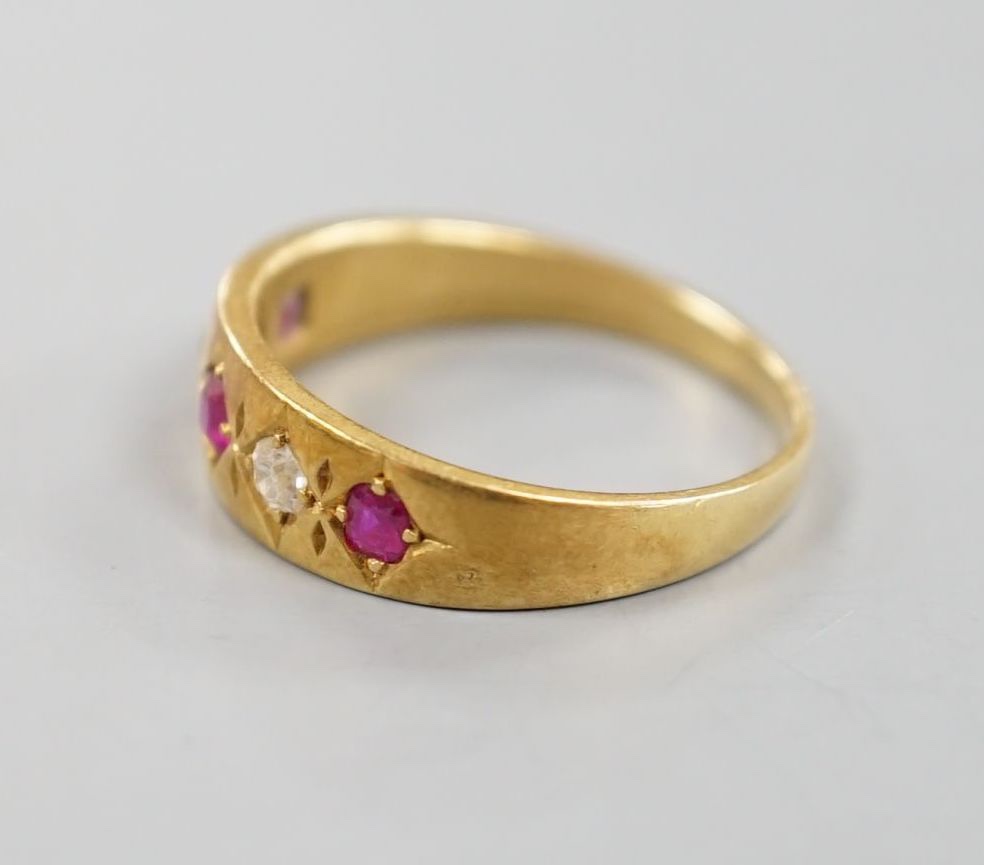 An early 20th century yellow metal and gypsy set three ruby and two stone diamond ring, size P, gross 4.3 grams.